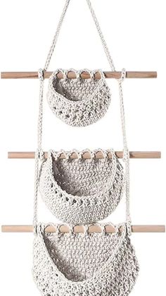 three crocheted baskets hanging from a wooden pole with two hooks on each side