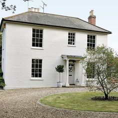 a large white house sitting on top of a lush green field