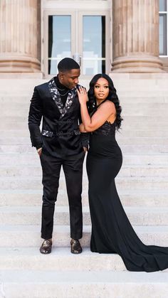 a man and woman in formal wear standing on steps with their arms around each other