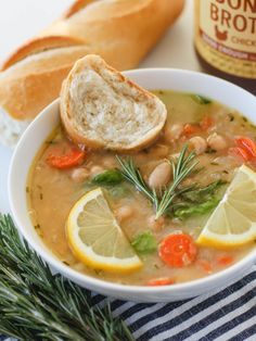 a bowl of soup with lemons, carrots and bread