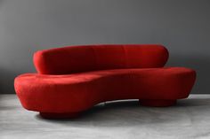 a red couch sitting on top of a cement floor