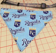 the kansas royals dog bandana is laying on a cutting board next to rulers