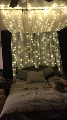 a person laying on top of a bed under a canopy with lights hanging from it