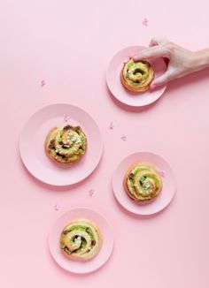 three plates with pastries on them and one being held by a person's hand