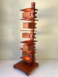 a tall wooden sculpture sitting on top of a white floor next to a light brown wall