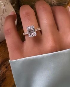 This breathtaking 3 Carat Emerald Cut Engagement Ring features an E VVS lab-grown or moissanite center stone, offering unparalleled brilliance and clarity. Flanking the center stone on each side are alternating small round diamonds and baguette diamonds, meticulously arranged in a three-time repeating pattern, adding an extra touch of sparkle and sophistication. The combination of the sleek emerald cut and the radiant side stones creates a stunning balance of elegance and modernity. Perfect for those who appreciate timeless beauty and luxurious craftsmanship, this ring is a true statement of love and commitment. Ring Details: *Ring Style: Emerald Cut Engagement Ring *Center Stone: *Carat Weight: 3.00 carats *Type: Lab-grown diamond or Moissanite *Cut: Emerald Cut *Color: E *Clarity: VVS *S Wedding Bands For Emerald Cut Rings, Emerald Cut Engagement Ring Silver, Emerald Cut Engagement Ring With Band, Emerald Engagement Ring Silver, Square Cut Engagement Ring, Commitment Ring, Custom Diamond Rings, Timeless Engagement Ring