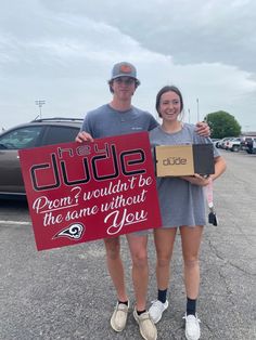 a man and woman standing in a parking lot holding a sign that says, dude