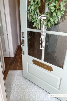 a door with a wreath on it and a ribbon hanging from the front door handle