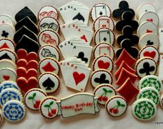 cookies decorated with playing cards and hearts are arranged on a white tablecloth in the shape of poker chips