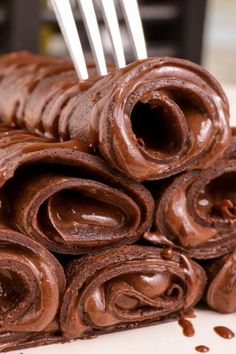 chocolate rolled up on top of each other with forks sticking out of the top one