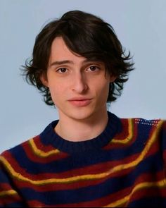 a young man wearing a striped sweater looks at the camera