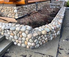 there is a stone bench made out of rocks on the side of a building with stairs leading up to it