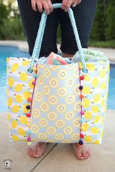 a woman is holding a large bag by the pool with her feet on the ground