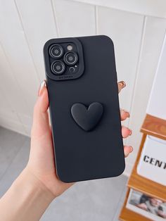 a person holding up a black phone case with a heart on the front and an air vent attached to it