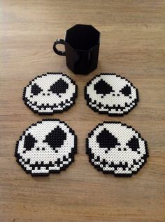 four black and white coasters sitting on top of a table next to a cup