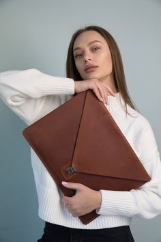 a woman is holding a brown leather case