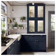 a kitchen with dark blue cabinets and white counter tops, along with potted plants