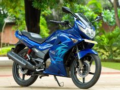 a blue motorcycle parked in front of some trees