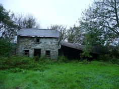 an old stone building sitting in the middle of a lush green field