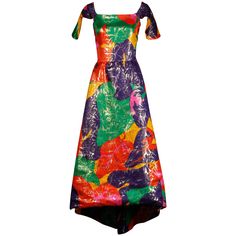 Incredible vintage metallic lame dress by Arnold Scaasi with a high low hemline and open back with chain detail. Petal shaped flap sleeves and tropical-inspired floral printed colorful silk fabric. Fully lined with rear zip and hook closure. Hidden side pockets. Fits like a modern size medium-large. The bust measures 38", waist 29.75", hips 46" and the total length 57" with a high low hem. Excellent vintage condition with no noted flaws. Made in USA. Arnold Scaasi, 1970s Clothing, Lame Dress, Silk Evening Gown, Off Shoulder Evening Dress, Satin Evening Dresses, Evening Gown Dresses, 1980s Dresses, Silk Print Dress