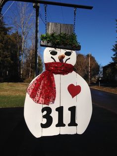 a snowman with a red scarf around his neck and number thirteen on it's face