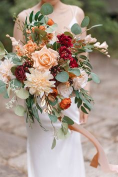 a bride holding a bouquet of flowers and greenery