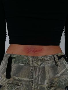 a woman's stomach with the word godly tattooed on her lower back side