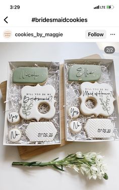 two decorated cookies in a box with writing on them and flowers next to each other