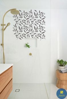 a bathroom with white tile and wood accents on the shower wall, along with a potted plant