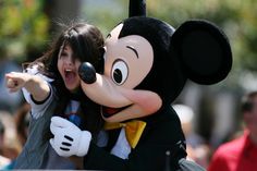 a woman is hugging a mickey mouse in front of a group of people on the street