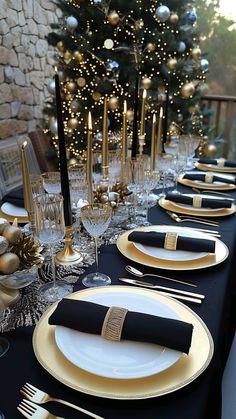 the table is set with black and gold place settings, silverware, and candles