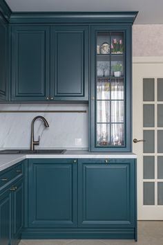 a kitchen with blue cabinets and marble counter tops, along with an open glass cabinet door