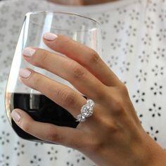 a woman's hand holding a wine glass with a diamond ring on it