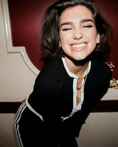 a smiling woman with her eyes closed in front of a red wall and white trim