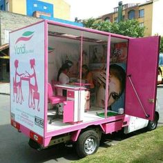 a pink food truck is parked on the side of the road with its doors open