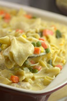 a spoon full of macaroni and cheese is being lifted from a casserole dish