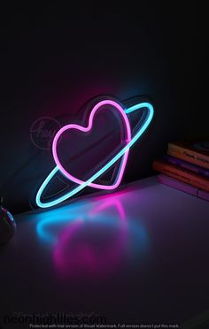 a neon heart shaped object sitting on top of a desk next to a computer mouse