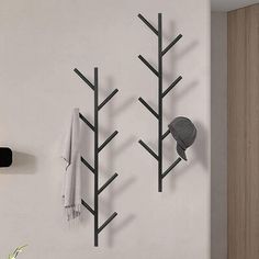 a wall mounted coat rack with three trees on it and a hat hanging from the hooks