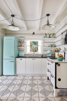 an old fashioned kitchen with blue refrigerator and tile flooring in the middle of it