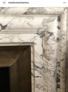 a white marble fireplace surround with black and gold details on the top part of it