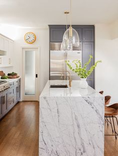 a kitchen with marble counter tops and an island in front of a clock on the wall