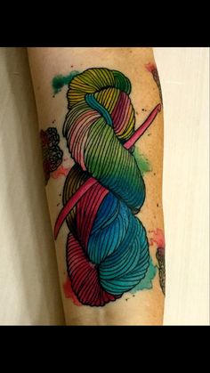 a woman's arm with a colorful yarn tattoo on it