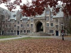 an old stone building with many windows and steps in the fall leaves on the ground