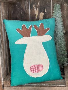 a blue pillow with a moose's head on it and a pine tree in the background