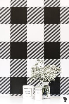 a vase filled with flowers sitting on top of a table next to a black and white checkered wall