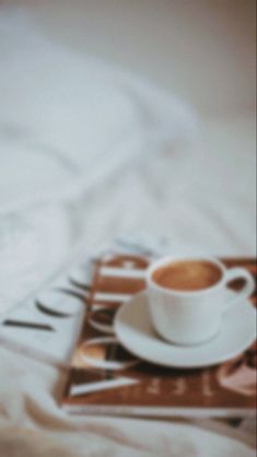 a cup of coffee sitting on top of a bed