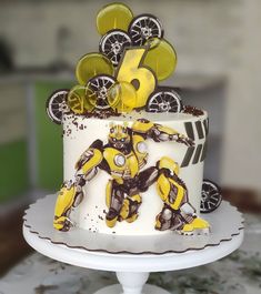 a cake decorated with yellow and black decorations on top of a white plate, sitting on a table