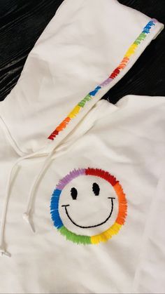 Hand embroidered rainbow smiley face hoodie!! Rainbow Shirt Design, Hoodie Hand Embroidery, Trendy Embroidered Hooded Hoodie, Rainbow Cotton Hoodie, Rainbow Cotton Hooded Hoodie, Casual Rainbow Hoodie For Streetwear, Cute Hooded Hoodie With Embroidered Logo, Trendy Hoodie With Embroidered Logo, Rainbow Hoodie For Winter Streetwear