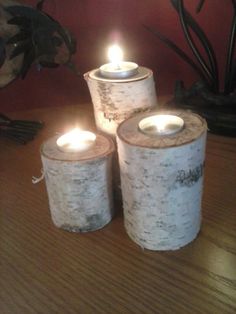 three lit candles sitting on top of a wooden table