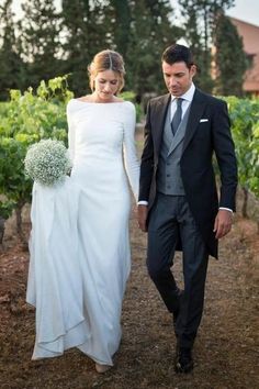 a bride and groom walking through the vineyard